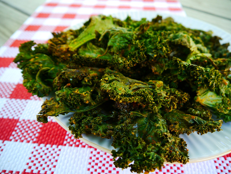 kale chips on a white plate sitting on a checkered white tablecloth