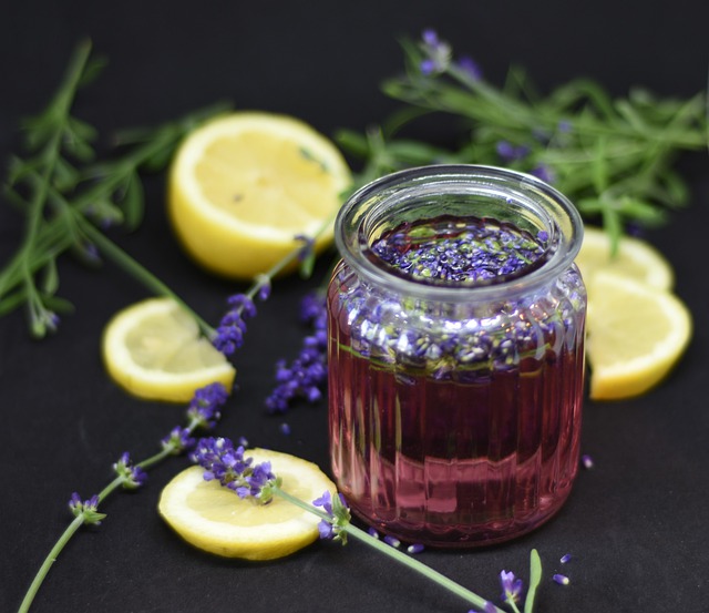 A jar of purple liquid with lavender buds on top and lemons around it